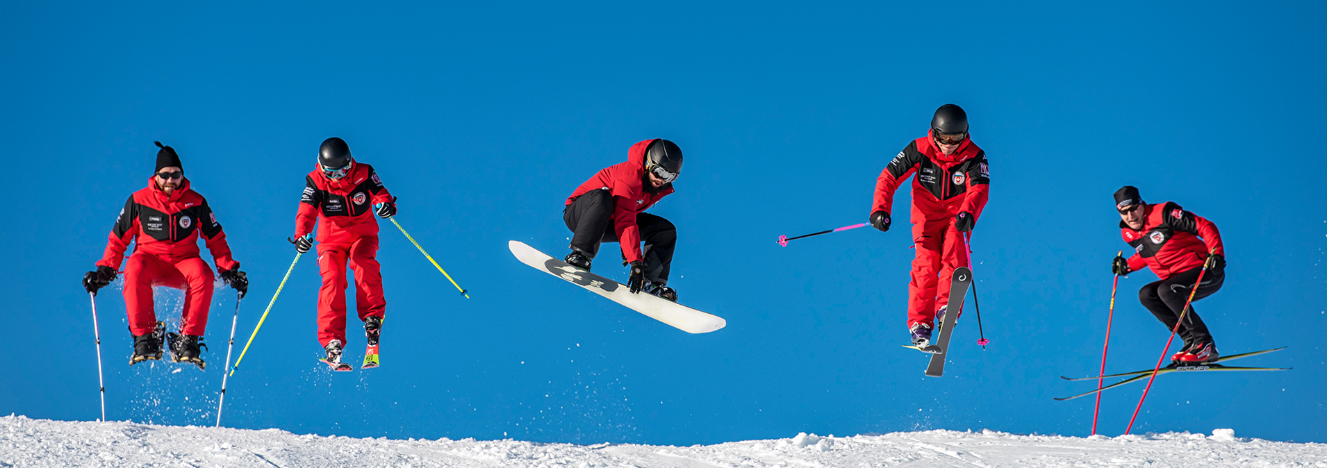 Ski- und Snowboardlehrer der Skischule Klosters springen auf der Piste 